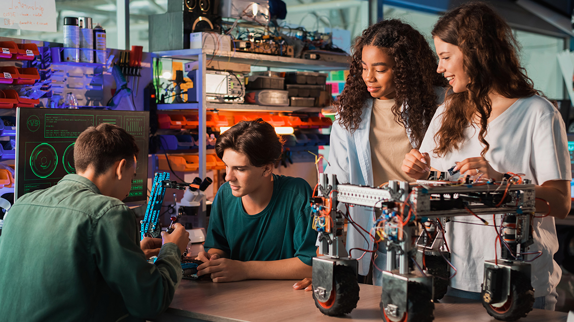 Vier junge Menschen arbeiten in einem Techniklabor an Robotics-Modellen