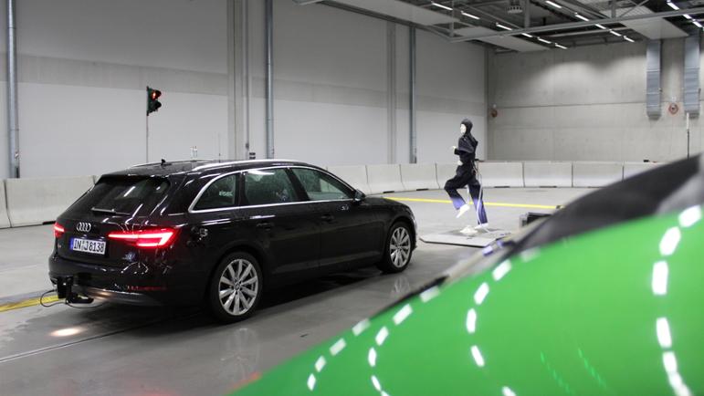 Ein autonomes Auto in einer Versuchshalle, das vor einem Fußgänger-Dummy bremst