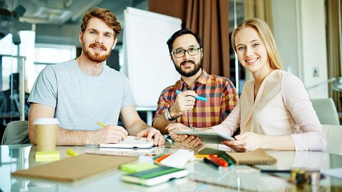 Drei Studenten besprechen sich an einem Tisch
