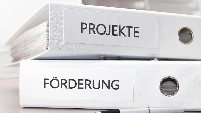 Zwei Aktenordner, beschriftet mit den Worten Förderung und Projekte, dazu ein Kugelschreiber