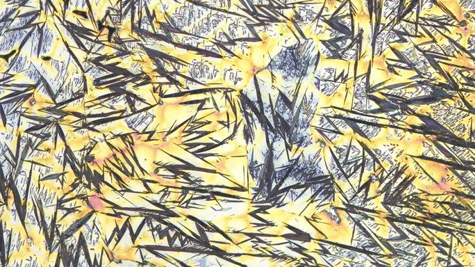 Mikroskopische Aufnahme von Metall, schwarze Zickzacklinien und hellblaue Flächen auf gelbem Untergrund.